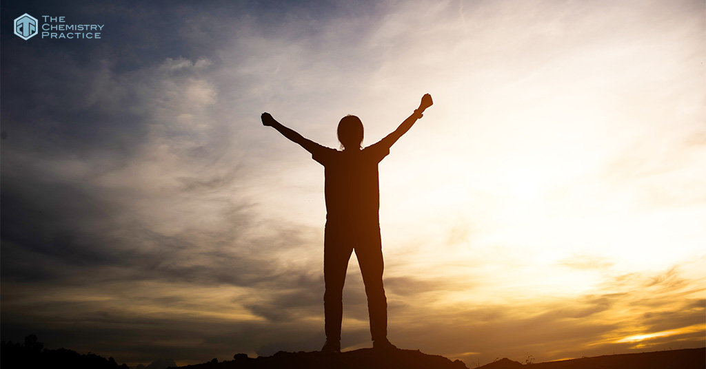 Student silhouette celebrating academic success against a sunset.