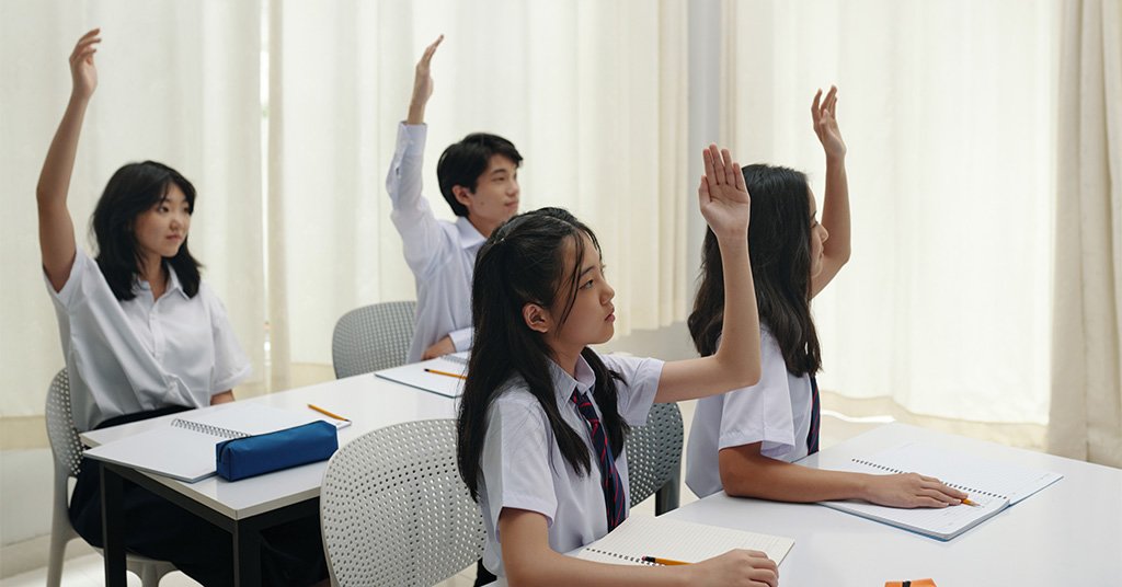 Students raising hands to answer questions in chemistry class.